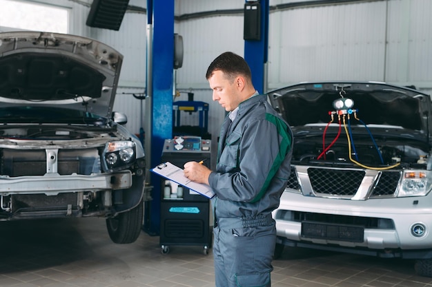 Mechanic maintaining car record on clipboard at the repair shop.