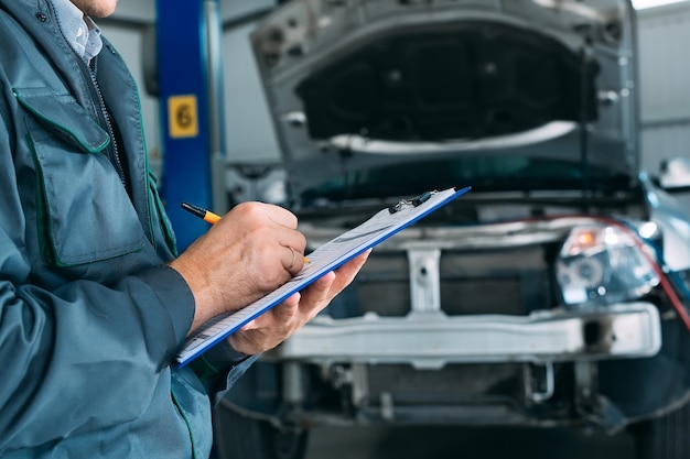 Mechanic maintaining car record on clipboard at the repair shop