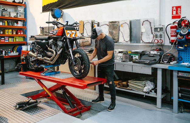 Foto l'uomo meccanico controlla la moto su misura sulla piattaforma