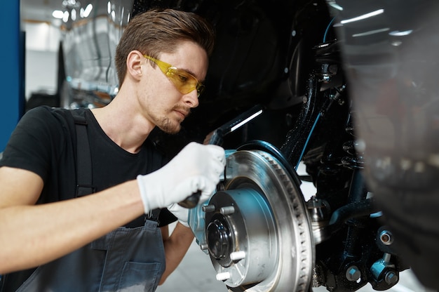 mechanic man checks brake disk in mechanical workshop