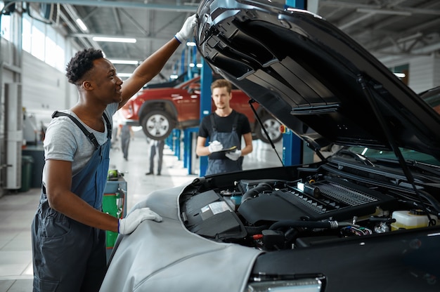 L'uomo meccanico ispeziona il motore in officina meccanica.