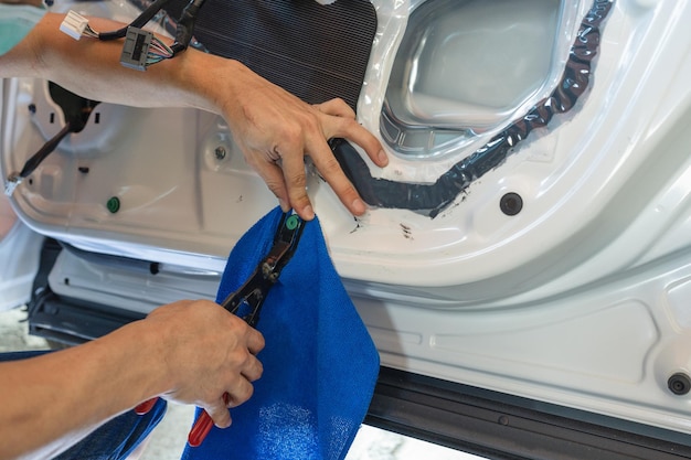 Mechanic man using wedge unpacking vehicle door part for checking damage in workshop