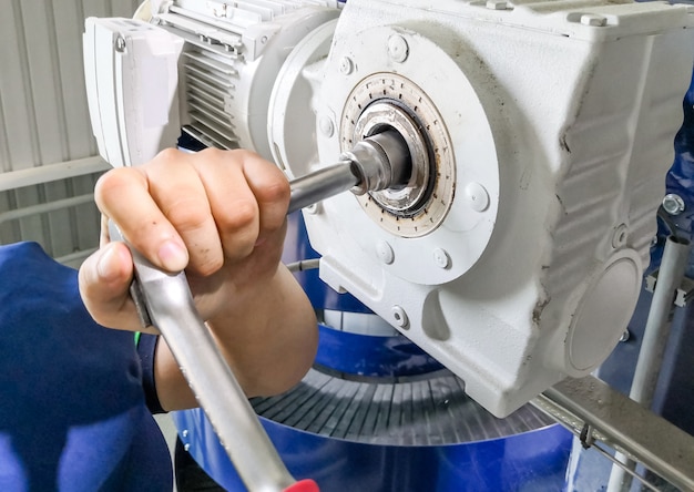 Mechanic man using a wrench to Repair or maintain the drive motor at machine