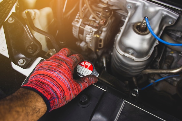 Mechanic man with red glove is opening radiator cap of a car,Automotive maintenance concept.