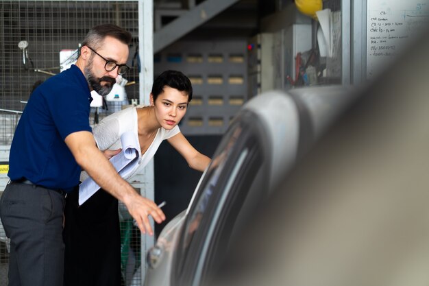 Il cliente meccanico uomo e donna controlla le condizioni dell'auto prima della consegna. garage della stazione di manutenzione della riparazione dell'automobile.