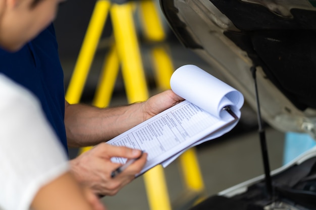 Mechanic man and woman customer check the car condition before delivery. automobile repair maintenance station garage.