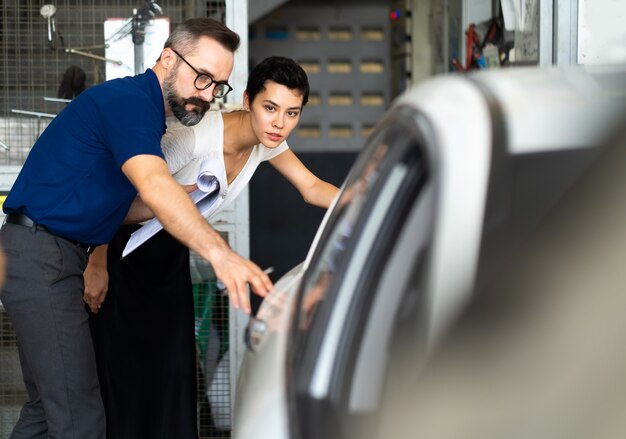 Mechanic man and woman customer check the car condition before delivery. automobile repair maintenance station garage.