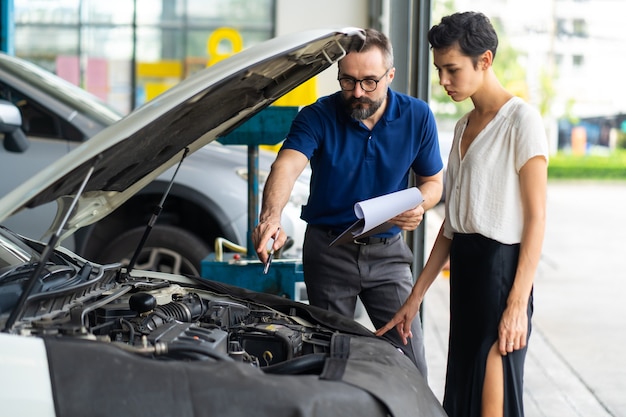 Mechanic man and woman customer check the car condition before delivery. automobile repair maintenance station garage.