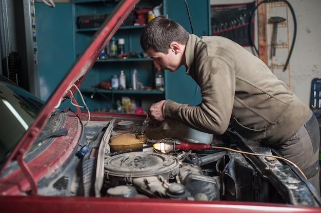 Mechanic man worker pouring antifreeze in the cooling system