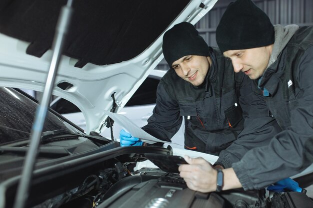 Mechanic men with wrench repairing car at workshop.