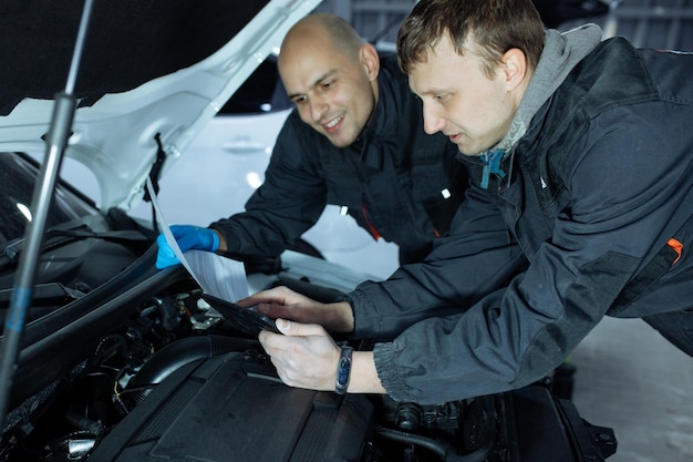 Photo mechanic men with wrench repairing car at workshop.