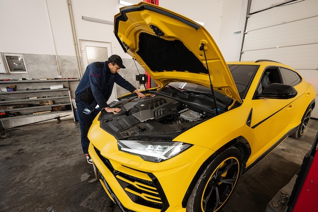 Foto meccanico cofano aperto di auto sportiva gialla suv