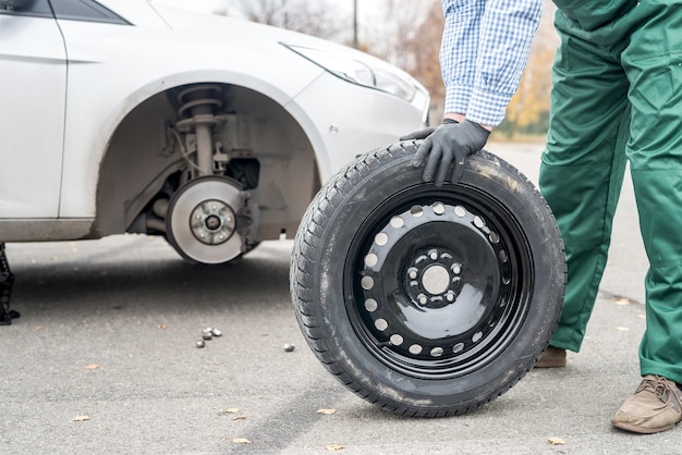 Mechanic posing with spare wheel on roadside