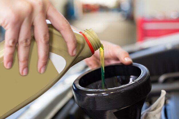 Mechanic pouring oil into car