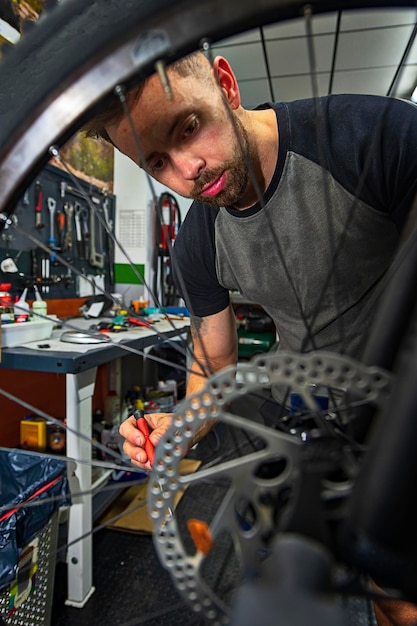 Foto meccanico che ripara biciclette in officina attrezzata