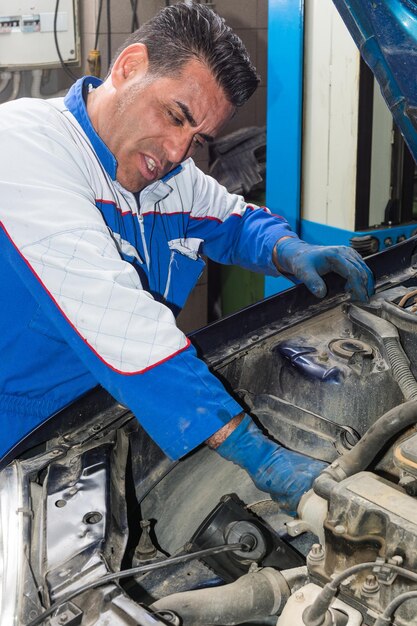 Foto meccanico che ripara il motore di un'auto in garage