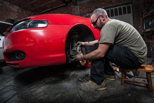 Foto meccanico che ripara l'auto in garage