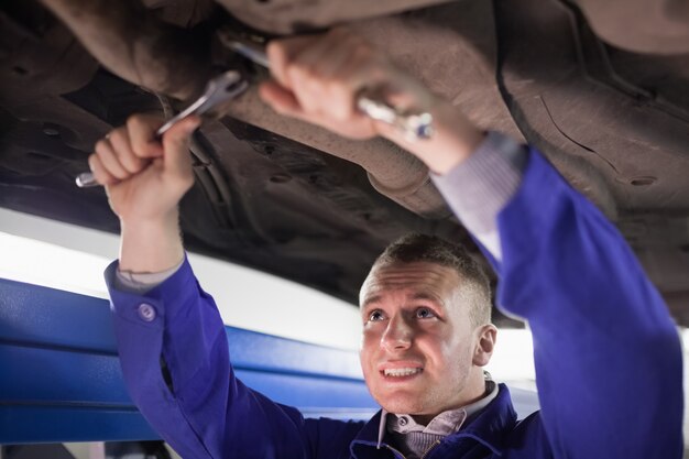 Mechanic repairing a car while using tools