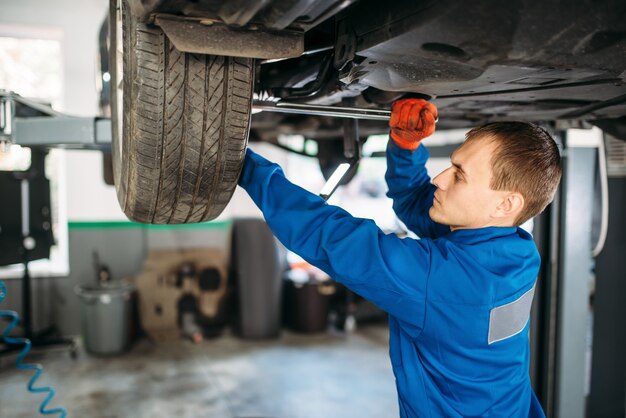 Mechanic repairs the suspension, car on the lift