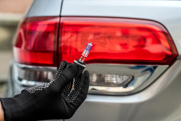 The mechanic's hands hold halogen car bulbs against headlight, repair auto