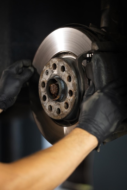 Mechanic at service station checks the brake and steering systems strong man checks for wear