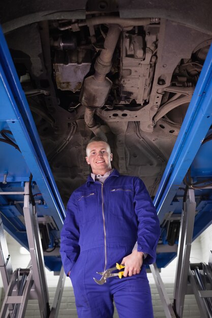 Photo mechanic standing up below a car