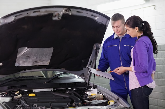 Mechanic standing with a clipboard next to a client