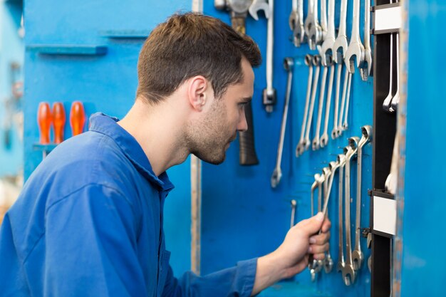 Mechanic taking a tool from wall at the repair garage