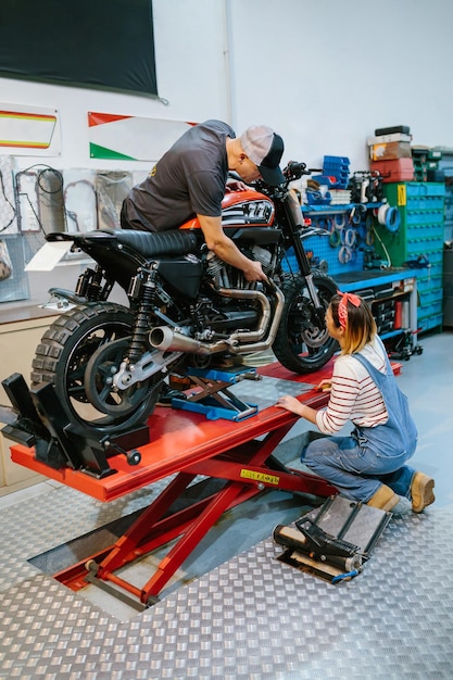 Foto squadra di meccanici che esamina il motore della moto in fabbrica