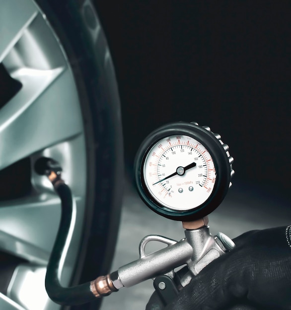 Mechanic testing the tire pressure of a car with tire pressure gauge in the auto repair garage