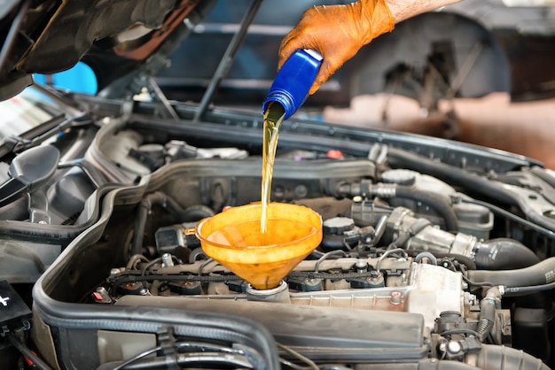 Mechanic topping up the oil in a car