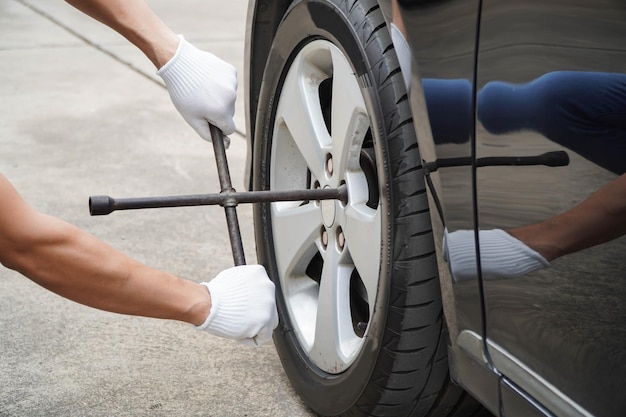 Mechanic uses a cross wrench to tighten the wheel nutsconcept\
of wearing white gloves