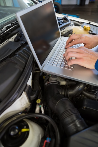 Foto meccanico che per mezzo del computer portatile sull'automobile