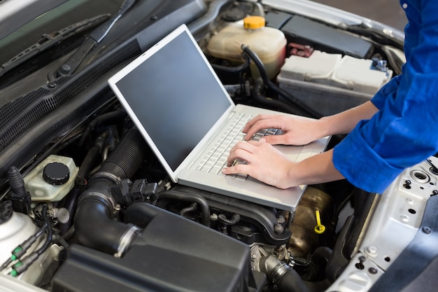 Meccanico che per mezzo del computer portatile sull'automobile