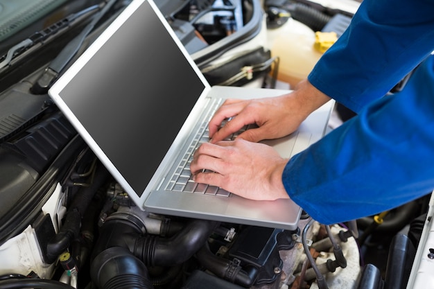 Mechanic using laptop on car