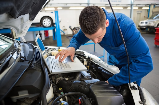 Meccanico che per mezzo del computer portatile sull'automobile