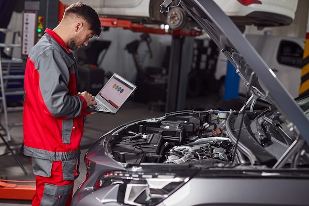 Photo mechanic using laptop and inspecting car in service