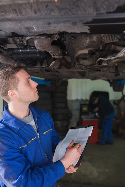 Foto meccanico con appunti esaminando auto