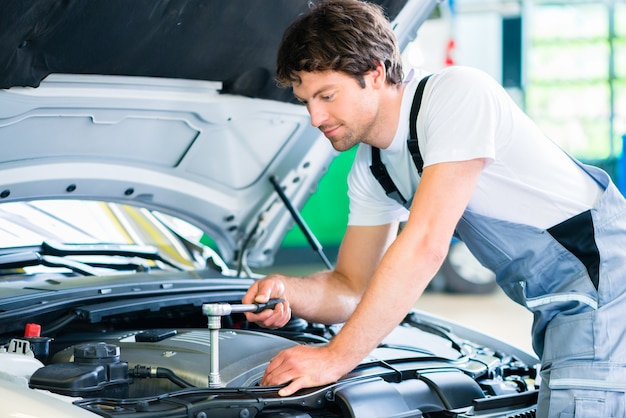 Mechanic with diagnostic tool in car workshop