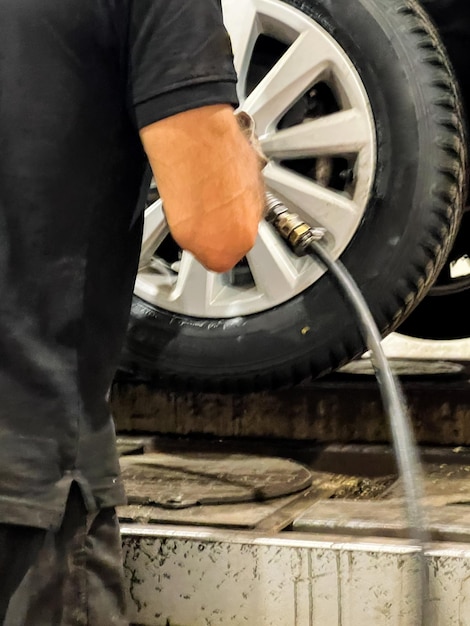 Mechanic with repairing car wheel in workshop Hands replace tires on wheels