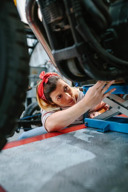 Foto donna meccanica che controlla la moto sulla piattaforma