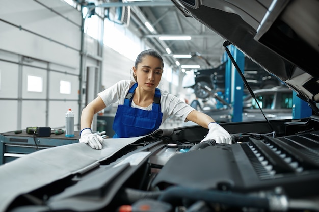 Mechanic woman checks engine in mechanical workshop