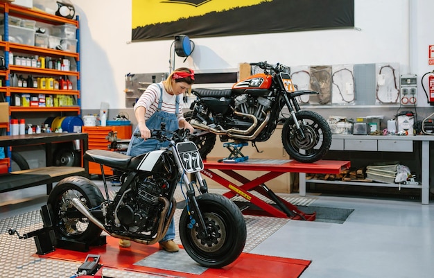 Photo mechanic woman placing custom motorcycle over platform