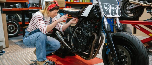 Photo mechanic woman repairing custom motorcycle on factory