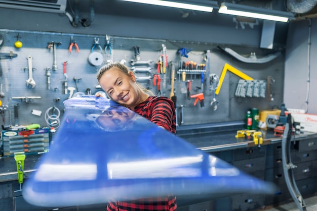 Mechanic woman repairing a snowboard in workshop 