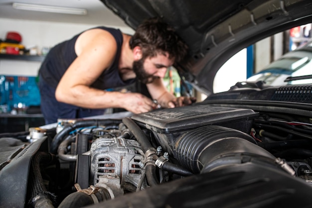 Mechanic at work on the car engine in a workshop