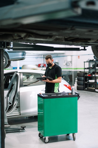 mechanic in a workshop checks the electronics of the car  software update with a modern compute