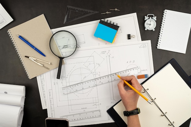 Mechanical drawing on sheets of paper Hands on the table top view Workflow of an architect engineer Write and draw Ruler pencil notebook