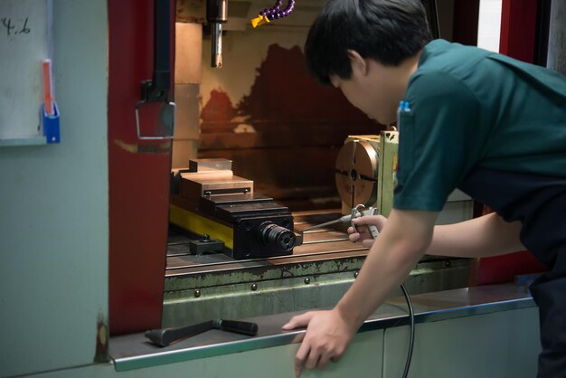 機械工具の工場で働く機械技師仕事でアジアの旋盤技術者タイの人々CNC機械を操作するアジアのハンサムな産業労働者