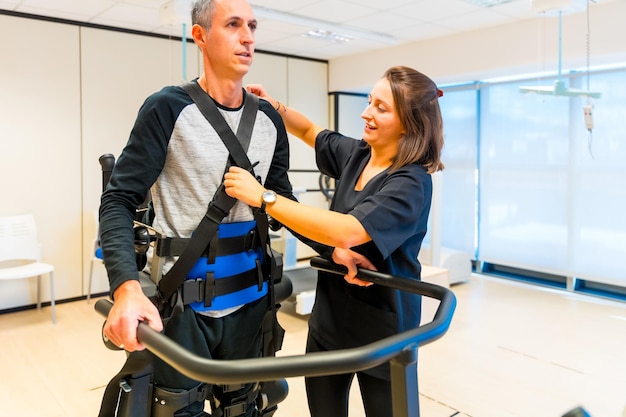 Foto esoscheletro meccanico assistente medica di fisioterapia femminile con persona disabile sollevata con scheletro robotico riabilitazione futuristica fisioterapia in un ospedale moderno